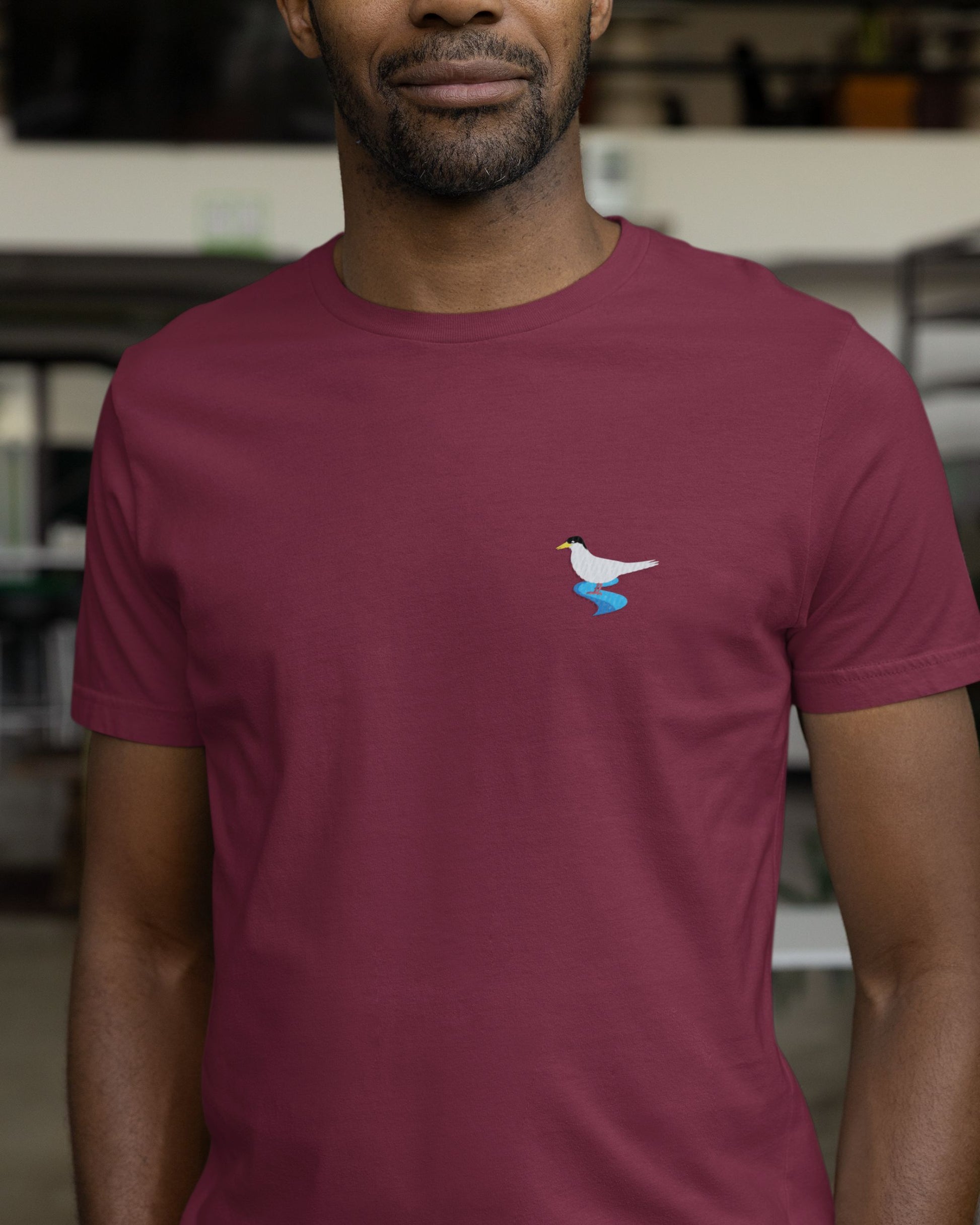 man wearing maroon  Supima cotton t-shirt with embroidered River Tern bird design by Tucktribe