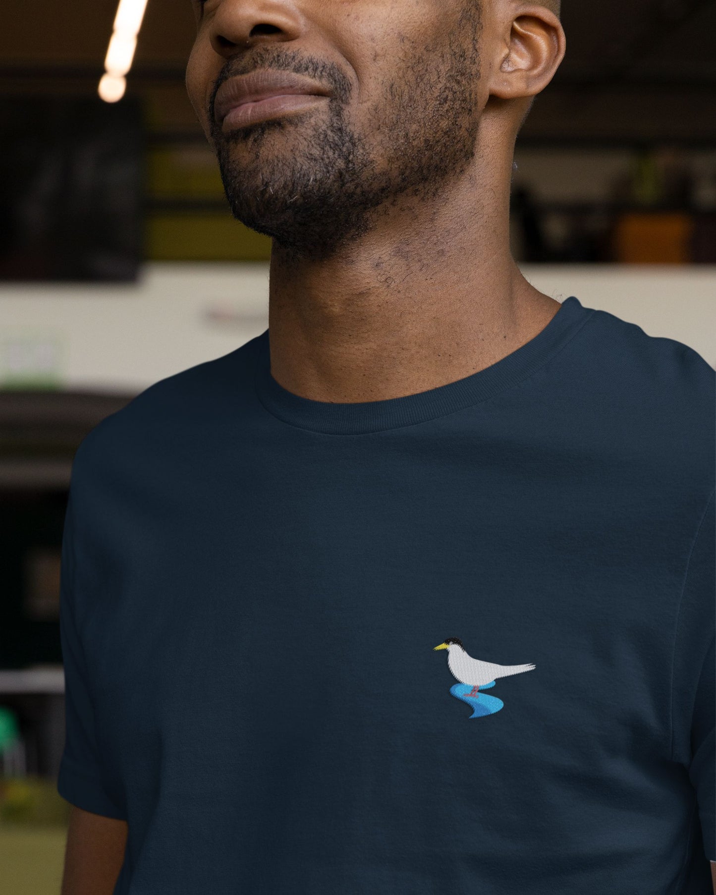 Man wearing Navy blue Supima cotton t-shirt with embroidered River Tern bird design by Tucktribe