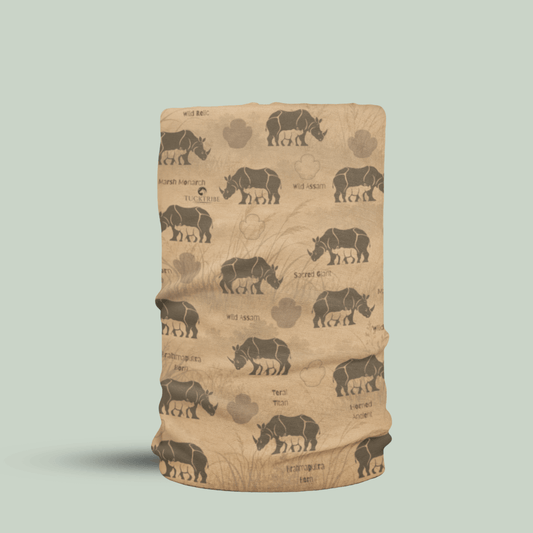 A beige tubular neck gaiter or face mask featuring a repeating pattern of dark brown greater one horned rhinoceros silhouettes, paw prints, and text, displayed on a solid light sage green background.
