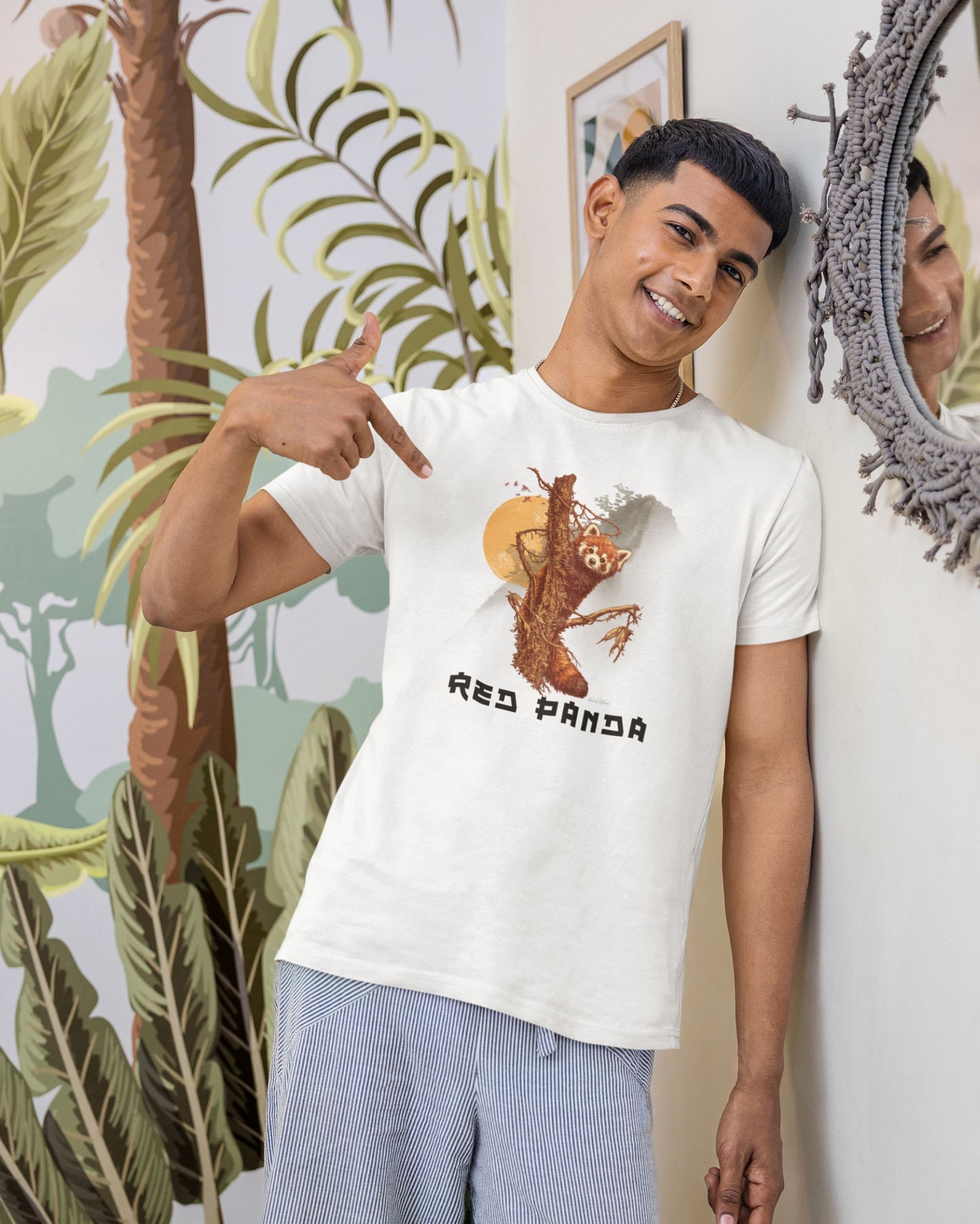 Person wearing a white tucktribe t-shirt with a red panda graphic, pointing at the shirt.