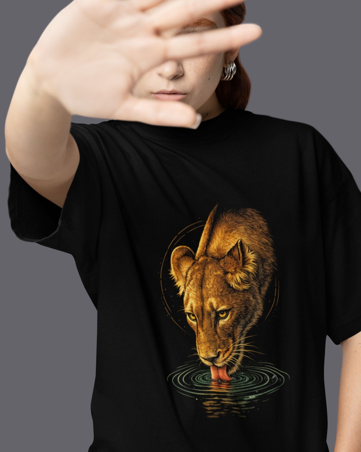 Person wearing a black tucktribe t-shirt with a lioness graphic design on a gray background
