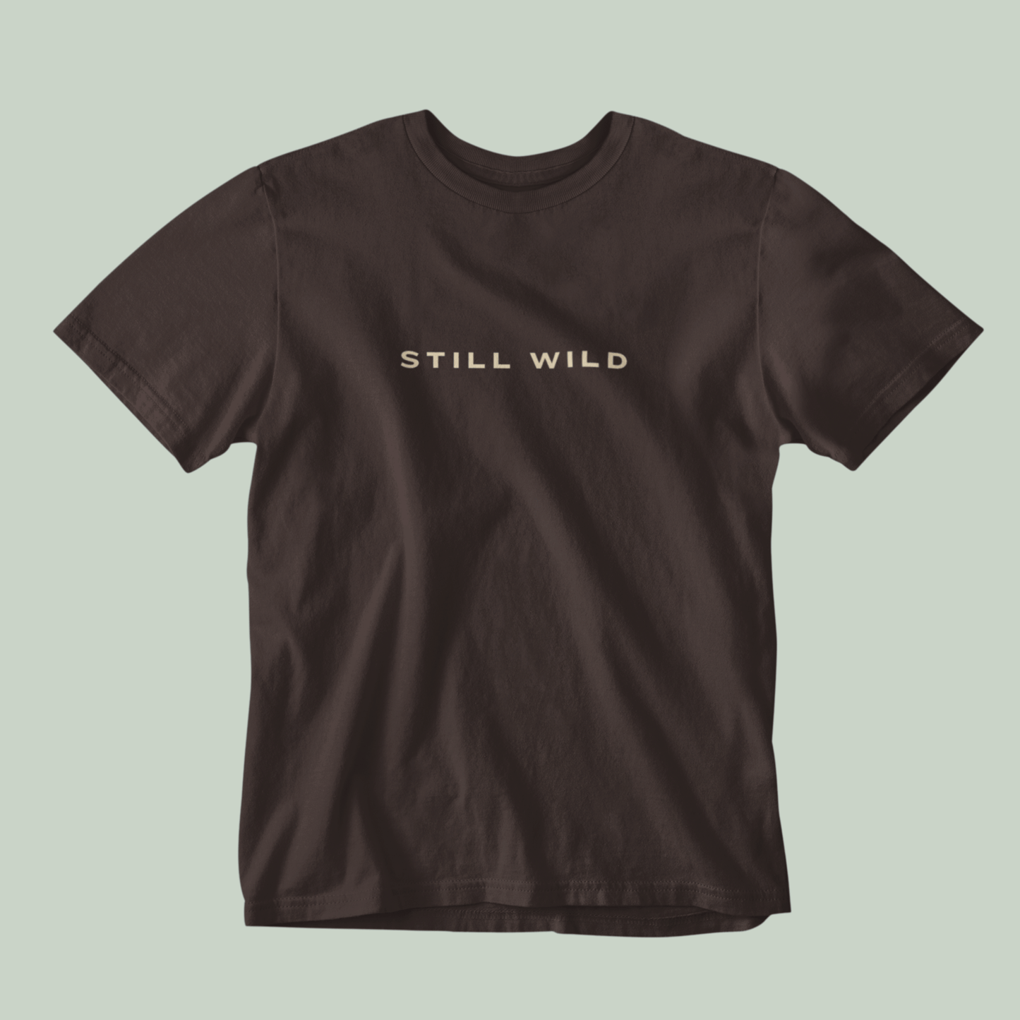 Tucktribe Brown t-shirt with 'STILL WILD' text on a light green background