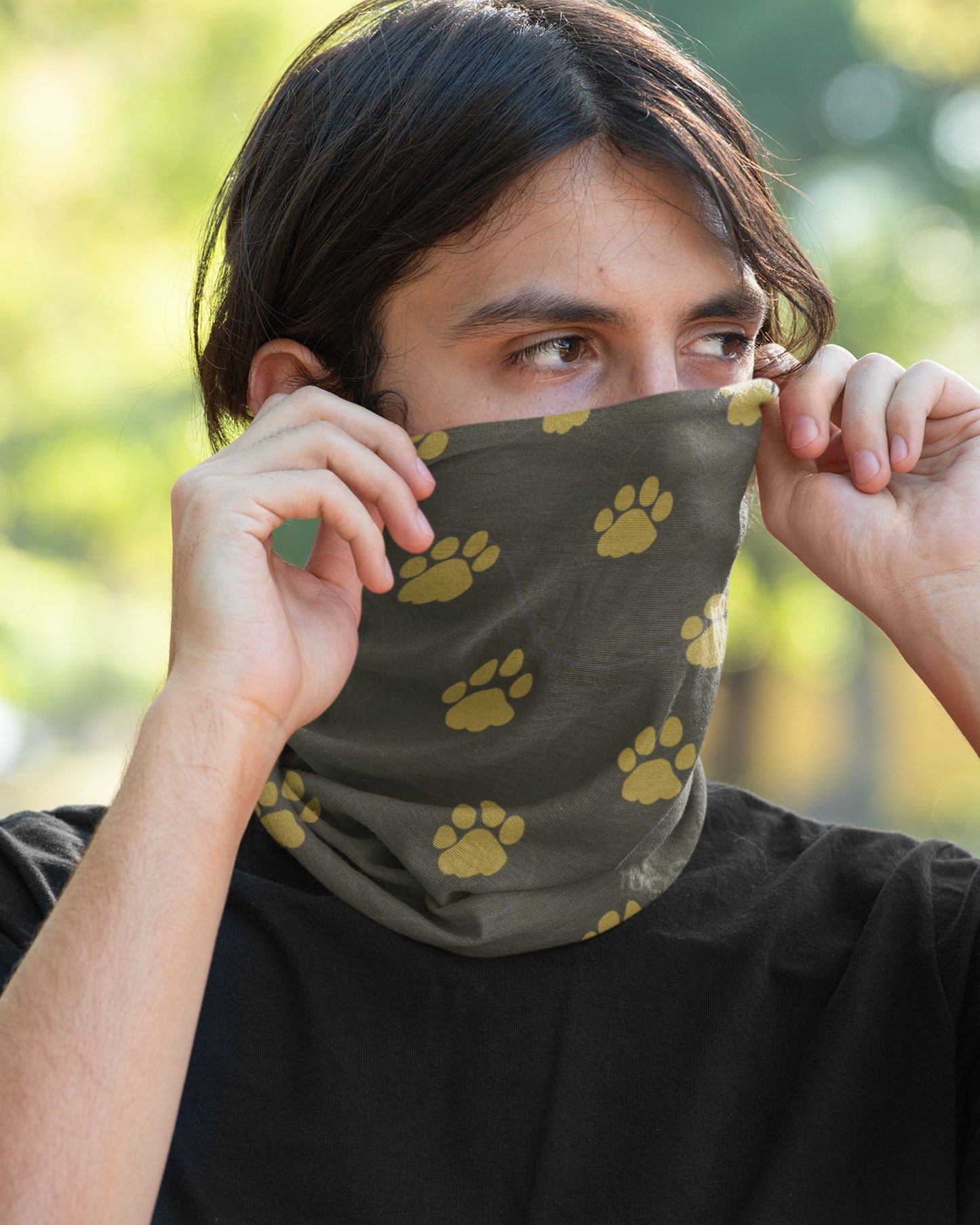 Person wearing a Deep green Tucktribe neck gaitor which has paw prints of a male and female tiger in the outdoor