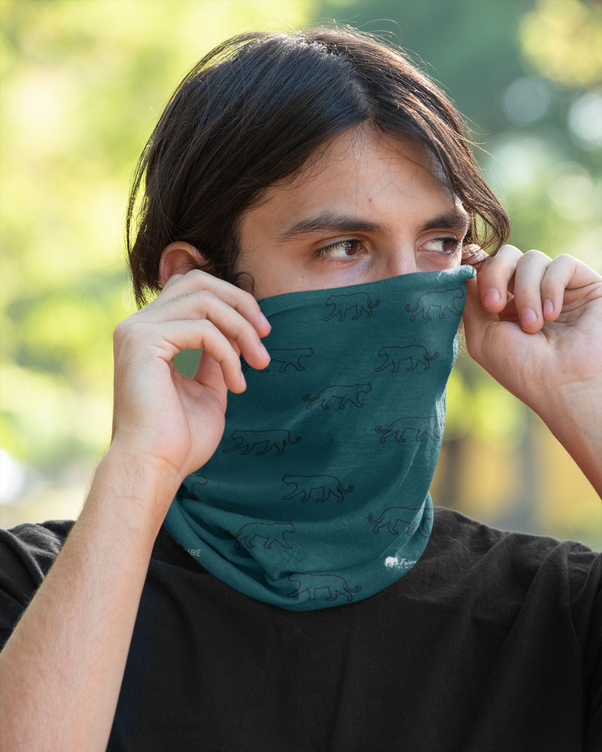 Person wearing a tucktribe teal neck gaiter with a blurred natural background