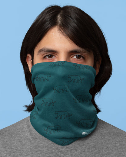 Person wearing a tucktribe teal neck gaiter with animal patterns against a blue background