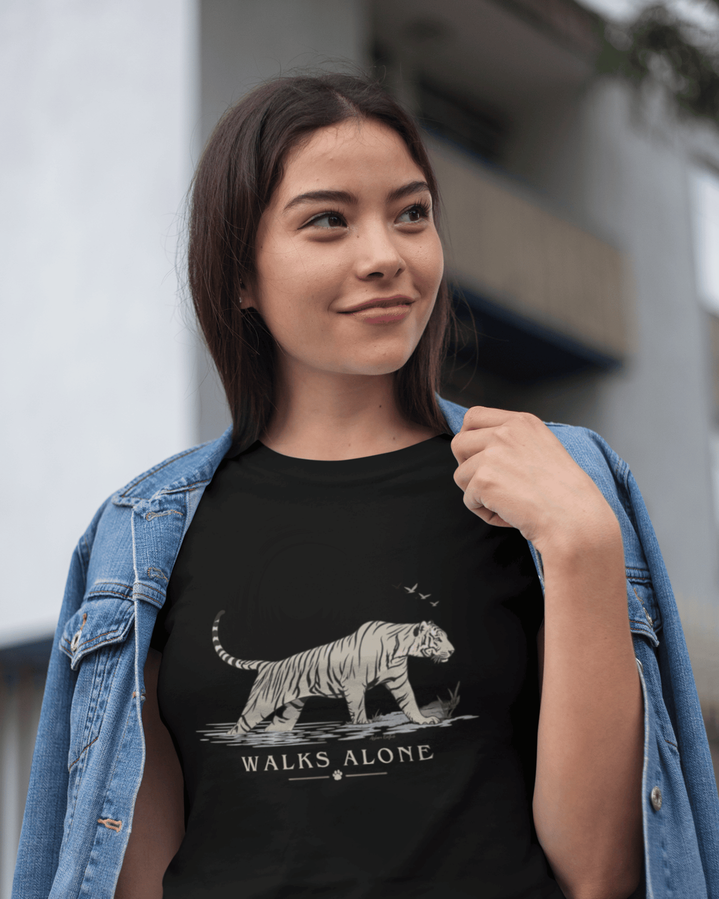 woman wearing a Black unisex tiger T-shirt with minimalist vintage wildlife artwork and “Walks Alone” design 
